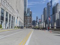 several people are walking through a deserted city street with tall buildings on either side of it