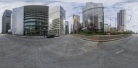 two cars sit in a parking lot and a building with many tall buildings stands next to the street