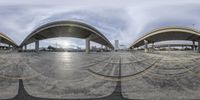 a fish eye view of an outside space with cars parked in the road and a bridge overpass