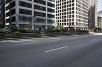 a man riding his bike down a city street next to tall buildings and flowers on the side of the road