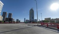 the empty parking lot of a city next to tall buildings in the background with many cars driving along