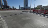 the empty parking lot of a city next to tall buildings in the background with many cars driving along