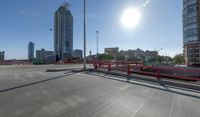 the empty parking lot of a city next to tall buildings in the background with many cars driving along