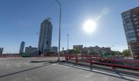 the empty parking lot of a city next to tall buildings in the background with many cars driving along