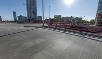 the empty parking lot of a city next to tall buildings in the background with many cars driving along