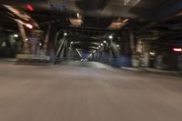 a blurry image of a street with a train coming up the platform below it