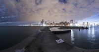 a concrete pier with many signs and clouds in the sky above a city at night