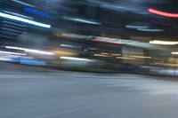 a very blurry looking car going around the corner at night time with city lights