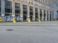 street lamps are at the edge of an empty road in front of large buildings with tall windows