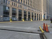 street lamps are at the edge of an empty road in front of large buildings with tall windows