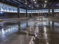 an empty airport parking garage with water on the floor and lights on above it,