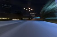 cars travel along the road at night in a blurry picture with neon lights on a building in the background