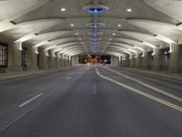 empty roadway with lights at night, with buildings in background in long tunnel in large city