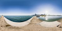 a panoramic view of city next to body of water with sand on the ground