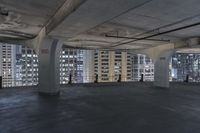 large, empty parking garage with many windows open to let in some light from the city skyline