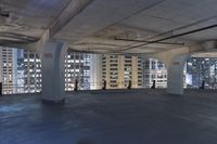 large, empty parking garage with many windows open to let in some light from the city skyline