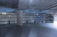 large, empty parking garage with many windows open to let in some light from the city skyline