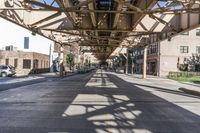 this is an urban street with parked cars on the road and the overhead structure is made to look like it is being a city