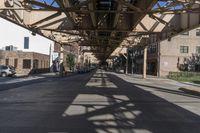 this is an urban street with parked cars on the road and the overhead structure is made to look like it is being a city