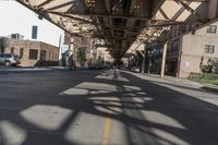 this is an urban street with parked cars on the road and the overhead structure is made to look like it is being a city