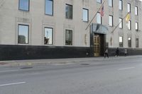 people walking in front of a large office building on the street in front of a building