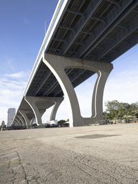 a view of a bridge from below with cars underneath it, looking up at it