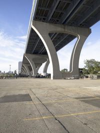 a view of a bridge from below with cars underneath it, looking up at it