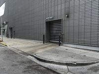 a white fire hydrant sitting next to a tall grey building on a sidewalk near an orange cone