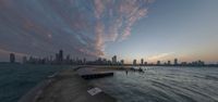 an orange sky and buildings are in the distance at a lakefront during sunset overlooking chicago