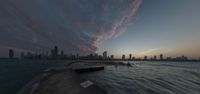 an orange sky and buildings are in the distance at a lakefront during sunset overlooking chicago