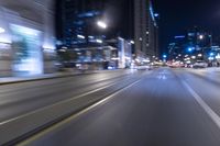 blurred car in the city at night time on a street with street lamps and high rise buildings