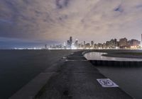 the city skyline is lit up on a dark day by the water's edge