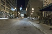 an empty city street and buildings with street signs at night time in the background are street lights