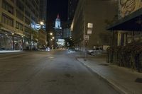 an empty city street and buildings with street signs at night time in the background are street lights