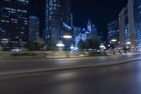 blurry motion picture of street with city buildings at night time in urban area of large city