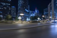 blurry motion picture of street with city buildings at night time in urban area of large city