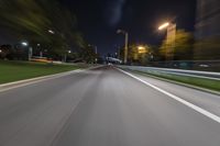 an empty street at night with blurred lights in the background and a car driving down the road