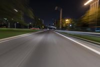 an empty street at night with blurred lights in the background and a car driving down the road