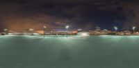 the night scene is of the stadium with cars driving by it and a clock tower with lights