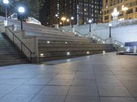 a man riding his skateboard across a walkway next to a building at night on a sidewalk