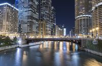 a river is seen between two buildings in a downtown area at night, with city lights on