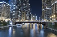 a river is seen between two buildings in a downtown area at night, with city lights on