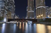 a river is seen between two buildings in a downtown area at night, with city lights on