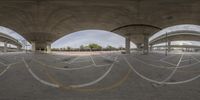 an overpass with various markings painted on the concrete and a road behind it, as viewed from the bottom