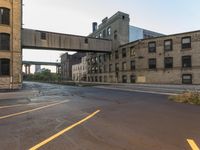 street next to a highway and old abandoned buildings with one going under a bridge in the middle