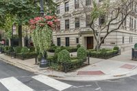 a street view in front of a building, with shrubs in the front of it