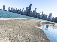 an empty sidewalk that leads to the city of chicago's skyline, which is in the middle of the lake