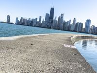 an empty sidewalk that leads to the city of chicago's skyline, which is in the middle of the lake