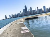 an empty sidewalk that leads to the city of chicago's skyline, which is in the middle of the lake