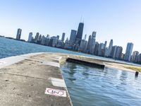 an empty sidewalk that leads to the city of chicago's skyline, which is in the middle of the lake